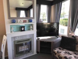 uma sala de estar com lareira e uma televisão de ecrã plano em Lime crescent golden sands em Mablethorpe