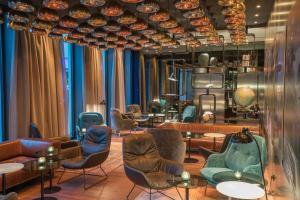 a waiting room with chairs and tables at Motel One Hamburg Airport in Hamburg