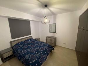 a bedroom with a bed with a blue comforter at Cosy apartment in Kato Paphos with pool access in Paphos City