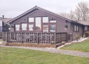 a log cabin with a wooden fence at Fenna Lakeside Lodge - Pine Lake Resort in Carnforth