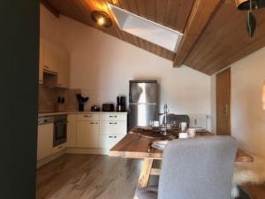 uma cozinha com uma mesa de madeira e cadeiras num quarto em Alpendomizil Reber 1 em Grassau