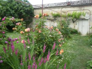 a garden with flowers in front of a building at DOMAINE DE BERTHEGILLE in Sablonceaux