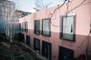 a pink building with green shutters on it at Hotel by Hyve Basel in Basel