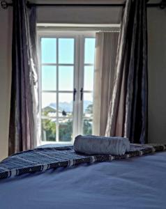 a bed with a towel on it in front of a window at Mond Kleine Guest House in Kleinmond