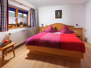 a bedroom with a bed with a red blanket and a window at Haus Michinglehen in Marktschellenberg