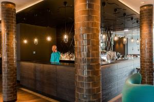a man standing behind the bar of a restaurant at Motel One München-Westend in Munich