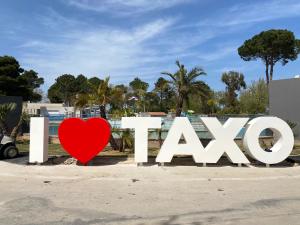 a red heart in front of the sign for the kiss at Camping Taxo Les Pins in Argelès-sur-Mer