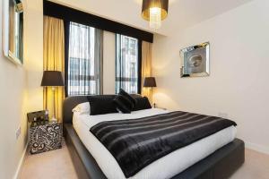 una camera da letto con un letto bianco e nero e finestre di Veeve - Brilliant Barbican a Londra