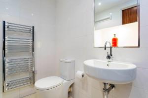 a white bathroom with a toilet and a sink at Veeve - Brilliant Barbican in London