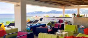 a patio with colorful chairs and a view of the ocean at Hotel Cala Luna in Cala Gonone