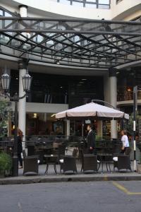 un restaurante con mesas, sillas y sombrilla en Tucuman Center Suites&Business en San Miguel de Tucumán