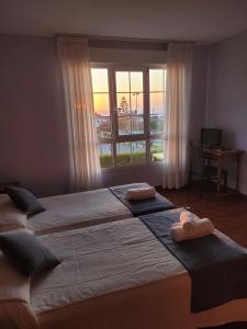 a bedroom with two beds with towels on them and a window at Hotel Restaurante el Fornon in Novellana