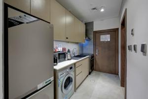 a kitchen with a refrigerator and a washer and dryer at ABAR HOTEL APARTMENTS DIP-1 in Dubai