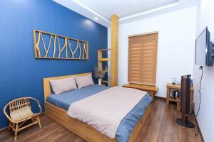 1 dormitorio con cama y pared azul en HomeStay Võ Thị Yến en Quy Nhon