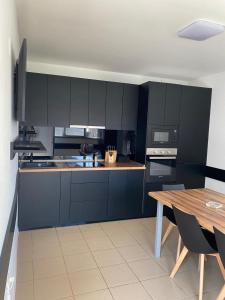 a kitchen with black cabinets and a wooden table at Vila Yanis Vama Veche in Vama Veche