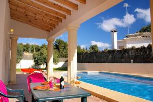 un patio con una mesa y una piscina en 3315 - Villa Carolina, en Casas de Torrat