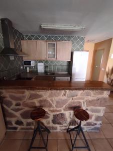 cocina con encimera de piedra y 2 taburetes en Casa Rural El Olmo, en Alobras