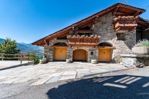 una casa in pietra con due porte garage su un vialetto di L'Atelier du Temps - Woodstone Villa ad Aosta