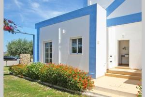 a blue and white house with flowers in front of it at CASA ALFARROBA, QUINTA DO PEROGIL, TAVIRA, ALGARVE in Tavira