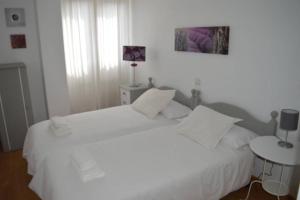 Dormitorio blanco con cama blanca y mesa en Apartamento turístico FARO DE LUNO, en San Vicente de la Barquera