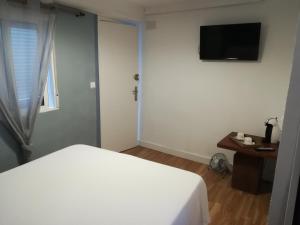 a bedroom with a white bed and a television at Hostal The Monkey Room in Marbella