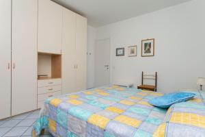 um quarto branco com uma cama e uma cadeira em N043 - Numana, bilocale con giardino em Sirolo