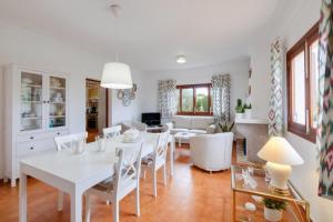 comedor y sala de estar con mesa blanca y sillas en Es Viola, en Santa Eugènia