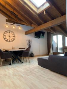 un soggiorno con tavolo, sedie e orologio di Breathtaking Waterfall Apartment nr 3 a Lauterbrunnen