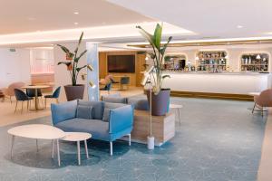 a lobby with blue chairs and tables and a bar at Hotel Cristina by Tigotan Las Palmas - Adults Only in Las Palmas de Gran Canaria