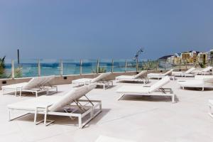 a row of lounge chairs on a roof with the beach at Hotel Cristina by Tigotan Las Palmas - Adults Only in Las Palmas de Gran Canaria