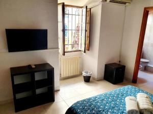 1 dormitorio con 1 cama, TV y ventana en Arc House Córdoba Only Adults, en Córdoba