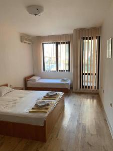 een slaapkamer met 2 bedden en 2 ramen bij Sozopol Dreams - Apartment №41 in Sozopol