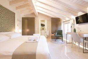 um quarto com uma cama branca, uma secretária e uma mesa em Hotel 1877 Sensaciones & SPA ADULTS ONLY em Albarracín