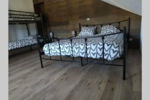 a bedroom with two beds and a wooden floor at Le repaire Ardennais in Rossart