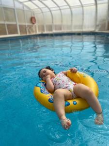 a little girl laying on a raft in a swimming pool at Dii Beach House - Casa de Férias com piscina interior aquecida in Torres Vedras