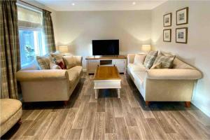 a living room with two couches and a tv at Beautiful 2 Bedroom, 2 Bathroom Flat with Parking. in Pitlochry