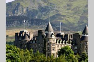an old castle with a mountain in the background at Beautiful 2 Bedroom, 2 Bathroom Flat with Parking. in Pitlochry