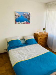 1 dormitorio con 1 cama con sábanas azules y una pintura en la pared en Logement entier vue sur mer !, en Palavas-les-Flots