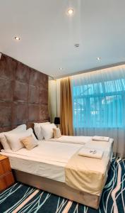 a large bed in a room with a large window at Hotel Vertigos in Tuzla