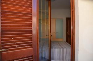 a glass door leading to a bedroom with a bed at Villetta con giardino in contesto riservato non lontana dal mare BEL01 in Agrustos