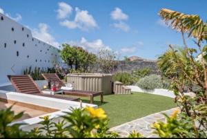 un jardín con 2 bancos y un patio de césped en Finca la costa en Tinajo