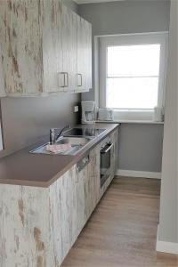 a kitchen with wooden cabinets and a sink and a window at Landhaus Braband Studios - Rugenbargsweg 17 in Cuxhaven