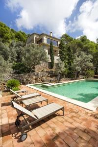 a swimming pool with benches and a house at Sa Casa des Mirador in Fornalutx