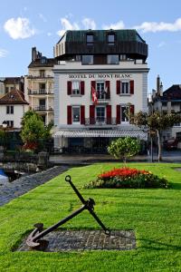 un orologio sull'erba di fronte a un edificio di Romantik Hotel Mont Blanc au Lac a Morges