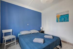 a blue bedroom with a bed and a chair at Maison de vacances avec jardin à 50 m de la plage in Narbonne