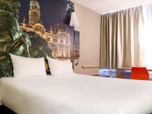 um quarto de hotel com uma cama grande com duas almofadas em ibis Lyon Gerland Merieux em Lyon