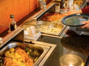 a buffet with many trays of food on a counter at Novotel Porto Gaia in Vila Nova de Gaia
