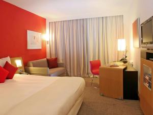 a hotel room with a bed and a desk and chair at Novotel Porto Gaia in Vila Nova de Gaia