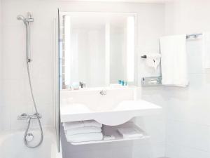 a white bathroom with a sink and a shower at Novotel Porto Gaia in Vila Nova de Gaia