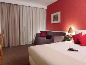 a hotel room with a bed and a couch at Novotel Porto Gaia in Vila Nova de Gaia